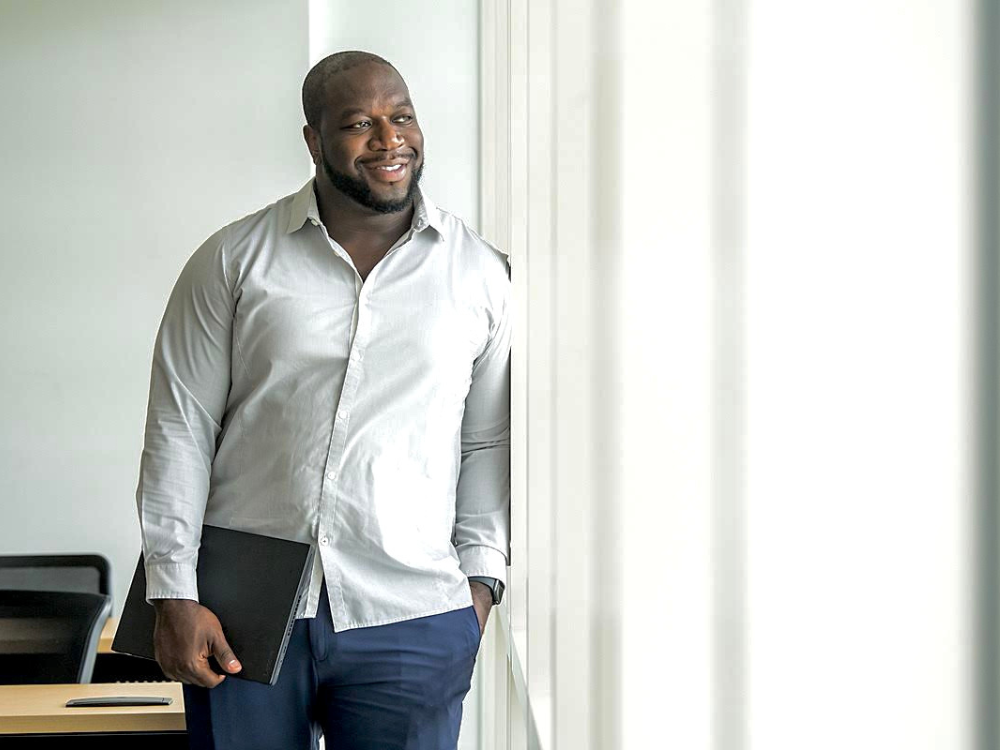 Devon Francis, Engineering Lab Technical Lead for Customer Experience at Victaulic, holds a laptop and looks out a window with a slight smile.